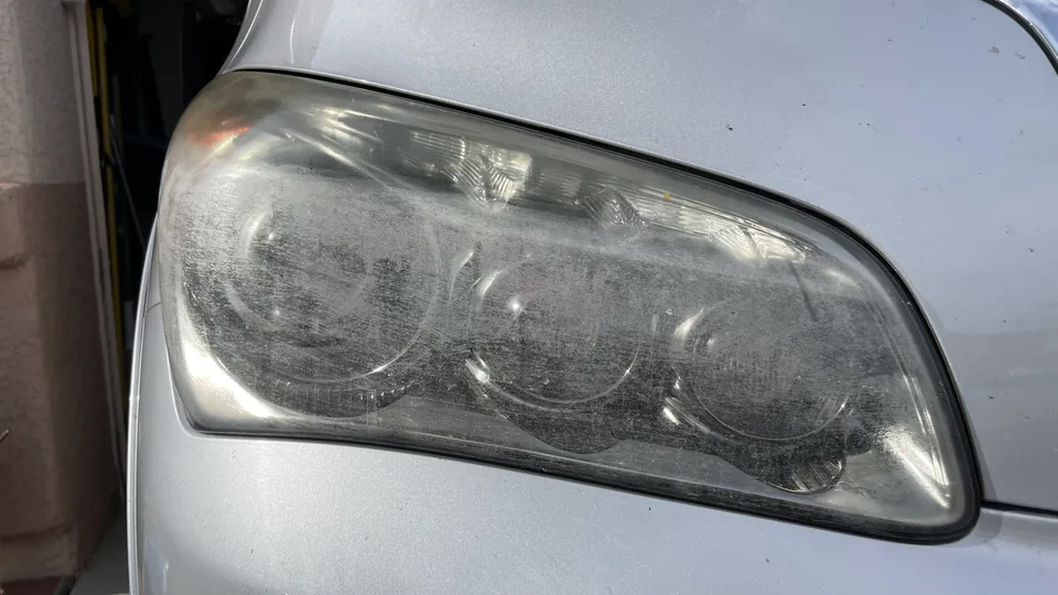 Before view of a headlight lens with visible haze or clouding and partly obscured internal lamp elements.