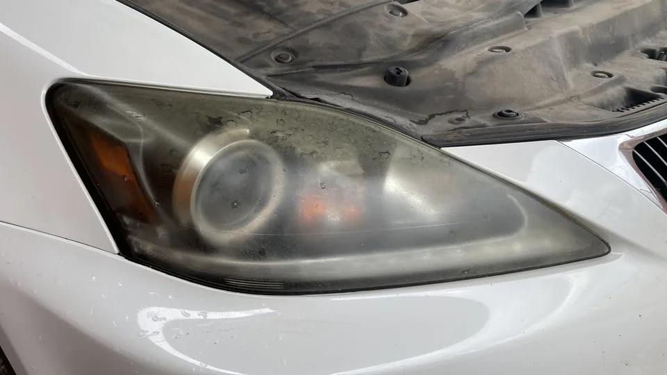 Before view of a headlight lens with visible haze or clouding and partly obscured internal lamp elements.